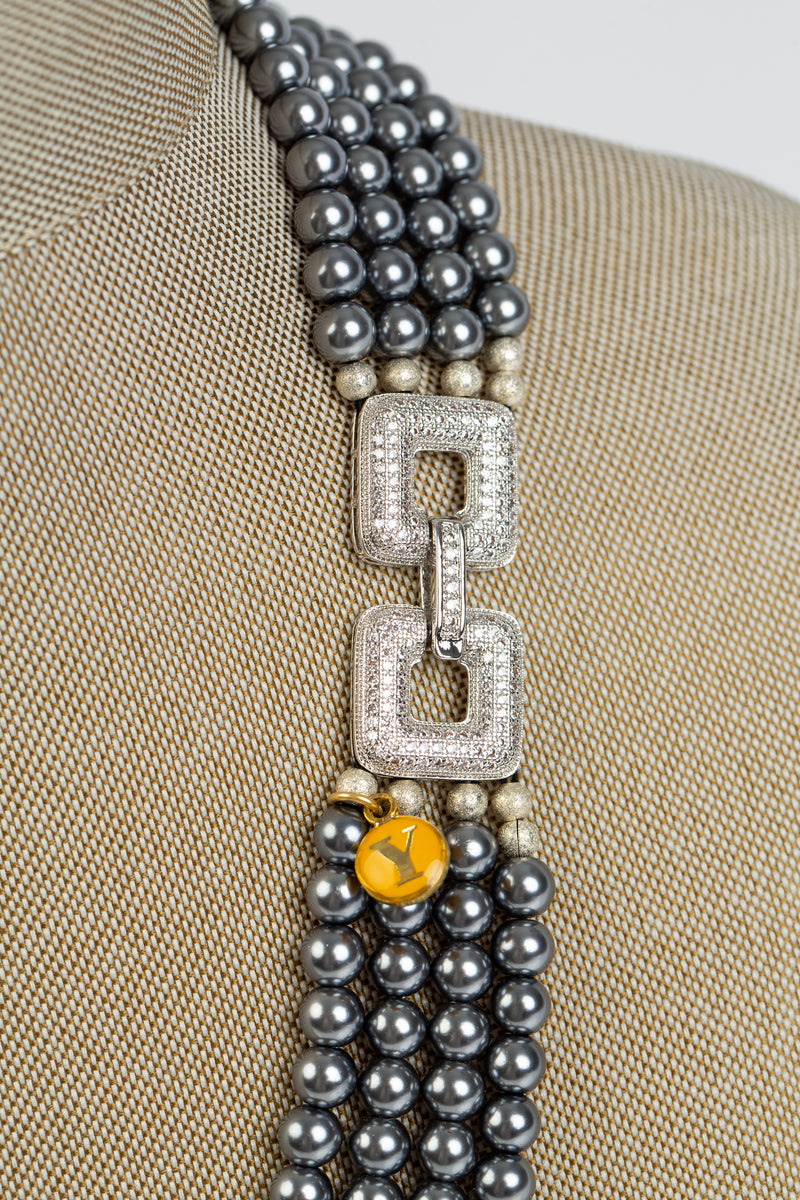 This necklace has four rows or grey and white pearls and is joined together with a crystal laden clasp.
