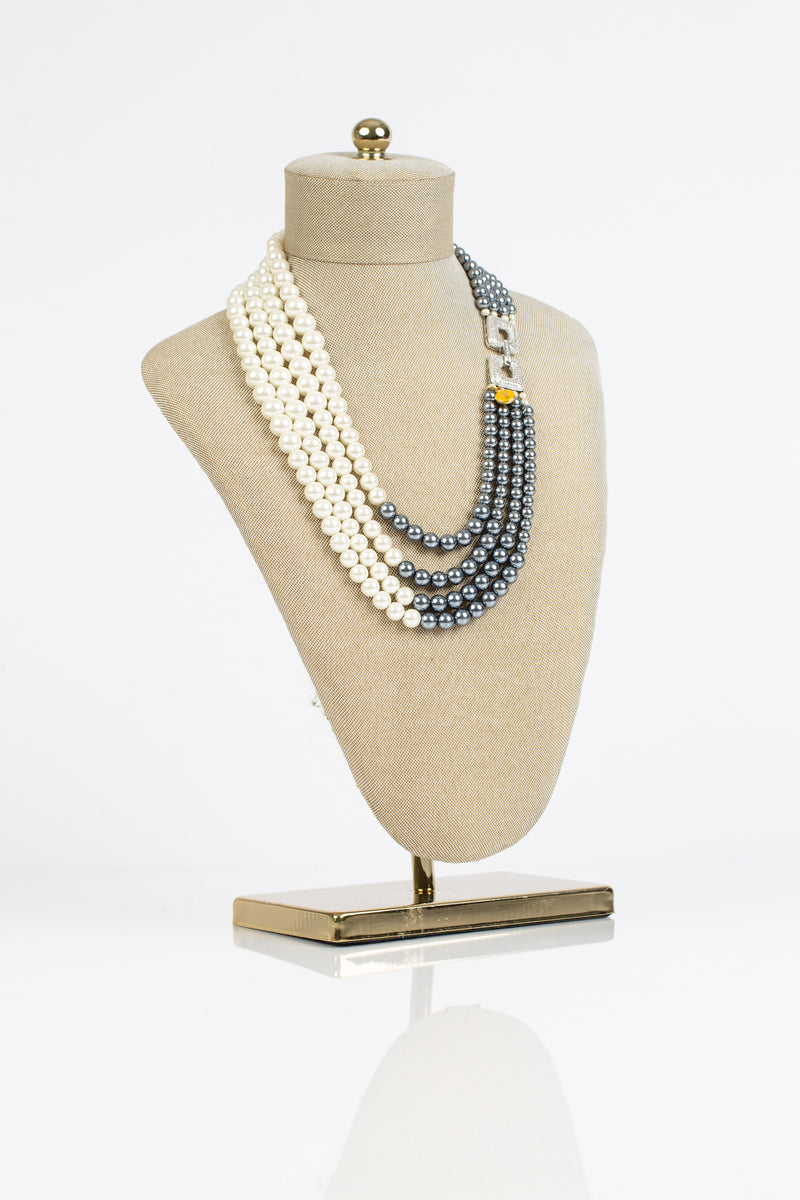 This necklace has four rows or grey and white pearls and is joined together with a crystal laden clasp.