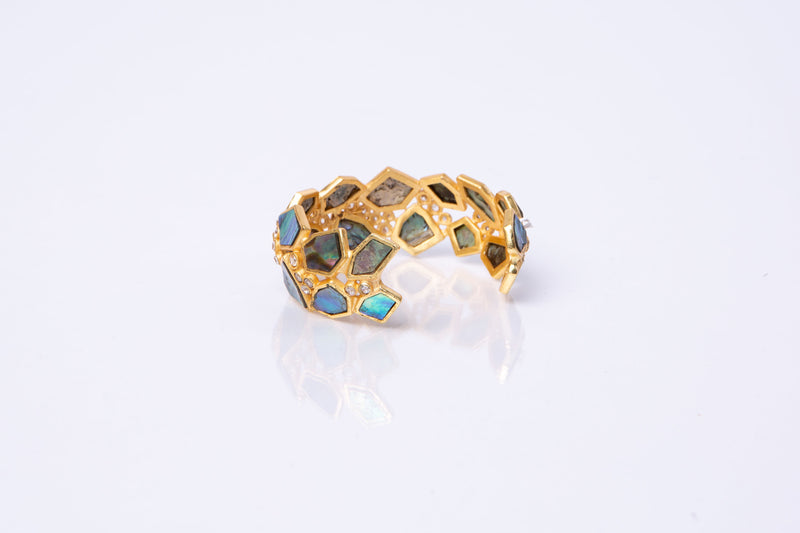 Asymmetrical natural Abalone stone is set in gold plated metal around Swarovski crystal to create this cuff that is easy to wear and fits most wrists. 