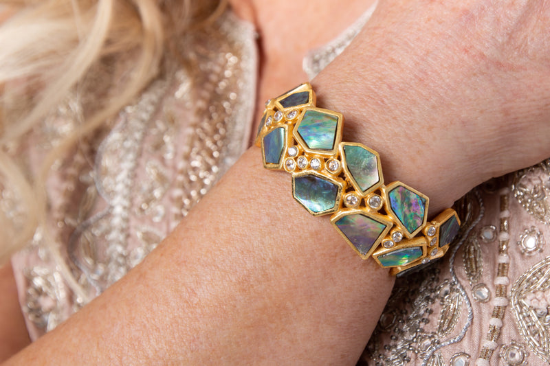 Asymmetrical natural Abalone stone is set in gold plated metal around Swarovski crystal to create this cuff that is easy to wear and fits most wrists. 