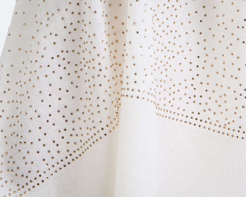 The Ethereal shawl is a hand woven light weight cashmere shawl that is embellished with gold Swarovski crystals over the entire length of the shawl. The shawl is sold in black or white. 