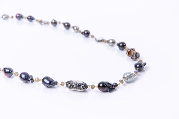 Natural black and grey baroque pearls encased in crystals. The necklace is 39 inches long with a toggle clasp. This necklace can be worn doubled or long. Hand crafted by artisans.