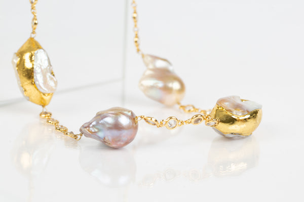The Julia necklace showcases baroque pearls encase in gold plating on the edges and are strung together on a Swarovski laced chain. It is an all occasion necklace. 