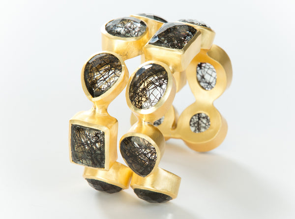 Two rows of black rutilated quartz set in brass and 18k electro-gold plated. Adjusts to fit most wrists.