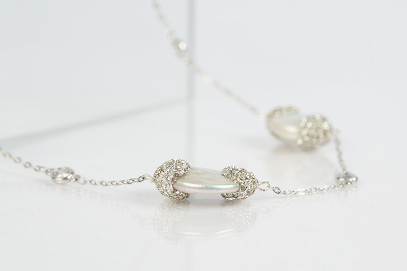 The Elsa flat pearls necklace is 39 “ long. Each freshwater pearl is encrusted with Swarovski  crystals. A toggle clasp allows for the necklace to be worn long or doubled. Image shows the necklace in white gold. 