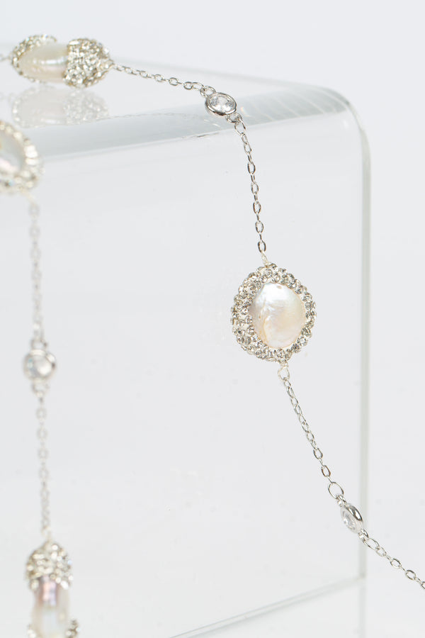 The Elsa flat pearls necklace is 39 “ long. Each freshwater pearl is encrusted with Swarovski  crystals. A toggle clasp allows for the necklace to be worn long or doubled. Image shows the necklace in white gold. 
