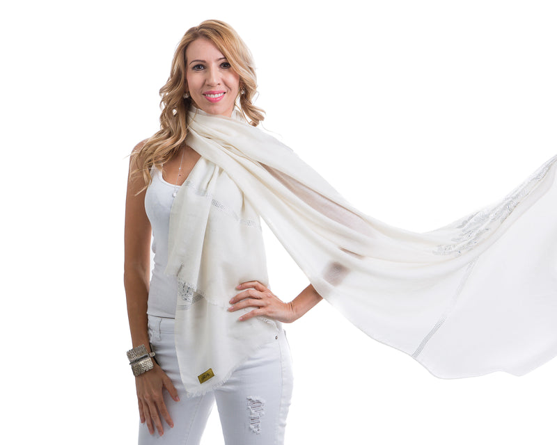 The image showcases the Yatra Halcyon Shawl that is offered in black and white. The cashmere shawl is decorated with large floral motifs at the two ends of the shawl with Swaravoski crystals in varied shapes and sizes. 