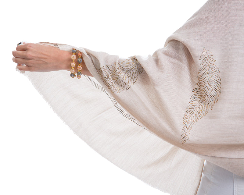 The Elixir cashmere shawl is embellished with Swarovski crystals. The crystals form a  leaf pattern all over the shawl. Two rows of crystals form a border along the two ends of the width. 