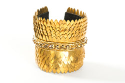 Wide gold plated cuff with feather cuts outs and a row of crystals in the center. The cuff is lined with soft leather for comfort. It is a significant piece that could be worn casually or to a black tie event.  It is offered in 3 finishes.