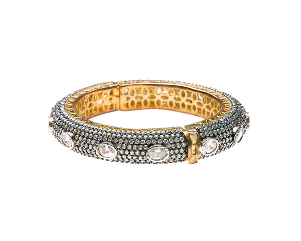 Hand-crafted bracelet with hinge in the center is easy to wear. The cuff is covered in Swarovski crystals of varying sizes. There is delicate filigree detail on the inside of the bracelet. The bracelet is 18k gold plated. 