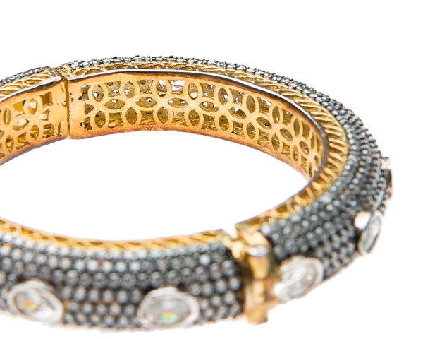 Hand-crafted bracelet with hinge in the center is easy to wear. The cuff is covered in Swarovski crystals of varying sizes. There is delicate filigree detail on the inside of the bracelet. The bracelet is 18k gold plated. 