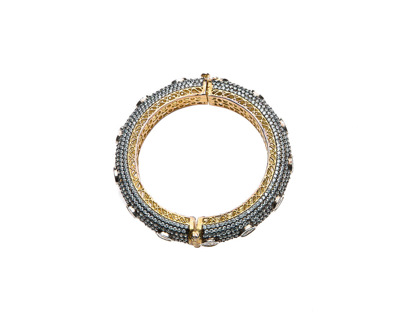 Hand-crafted bracelet with hinge in the center is easy to wear. The cuff is covered in Swarovski crystals of varying sizes. There is delicate filigree detail on the inside of the bracelet. The bracelet is 18k gold plated. 