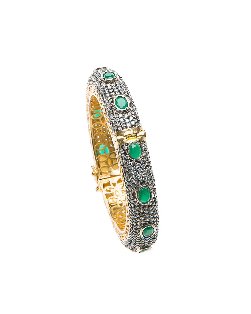 Hand-crafted bracelet with hinge in the center is easy to wear. The cuff is covered in clear Swarovski crystals. Semi precious green oval stones are spaced in intervals along the cuff.There is delicate filigree detail on the inside of the bracelet. The bracelet is 18k gold plated. 