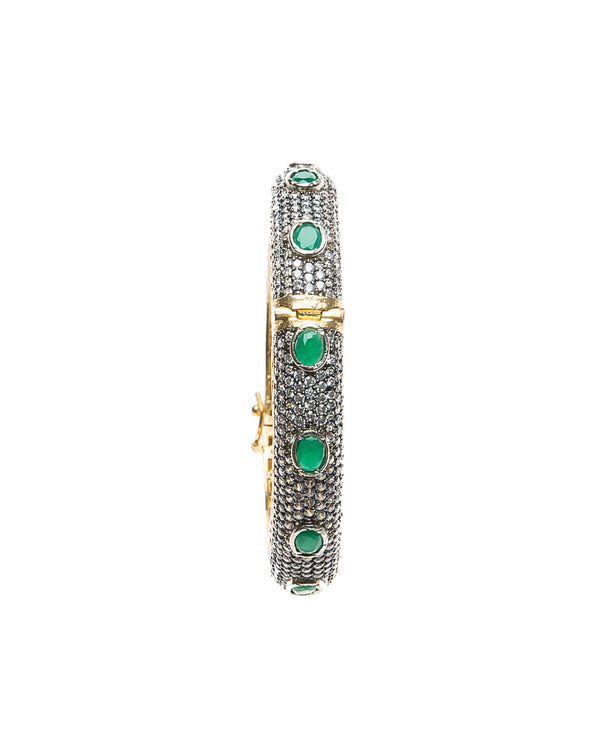Hand-crafted bracelet with hinge in the center is easy to wear. The cuff is covered in clear Swarovski crystals. Semi precious green oval stones are spaced in intervals along the cuff.There is delicate filigree detail on the inside of the bracelet. The bracelet is 18k gold plated. 