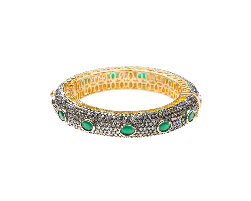 Hand-crafted bracelet with hinge in the center is easy to wear. The cuff is covered in clear Swarovski crystals. Semi precious green oval stones are spaced in intervals along the cuff.There is delicate filigree detail on the inside of the bracelet. The bracelet is 18k gold plated. 