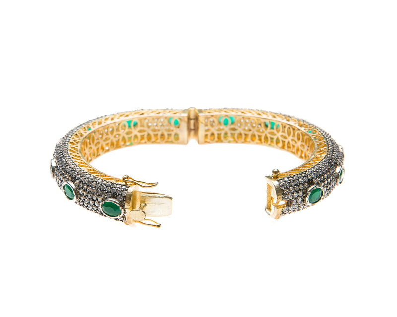 Hand-crafted bracelet with hinge in the center is easy to wear. The cuff is covered in clear Swarovski crystals. Semi precious green oval stones are spaced in intervals along the cuff.There is delicate filigree detail on the inside of the bracelet. The bracelet is 18k gold plated. 