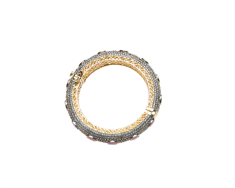 Hand-crafted bracelet with hinge in the center is easy to wear. The cuff is covered in clear Swarovski crystals. Semi precious red oval stones are spaced in intervals along the cuff.There is delicate filigree detail on the inside of the bracelet. The bracelet is 18k gold plated. 