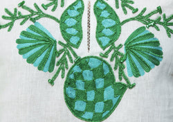 White linen tunic with substantial hand embroidery with faux coral detail. The embroidery is in either green, red or blue. Embroidery detail in around the neck, sleeves and at the bottom of the tunic. 