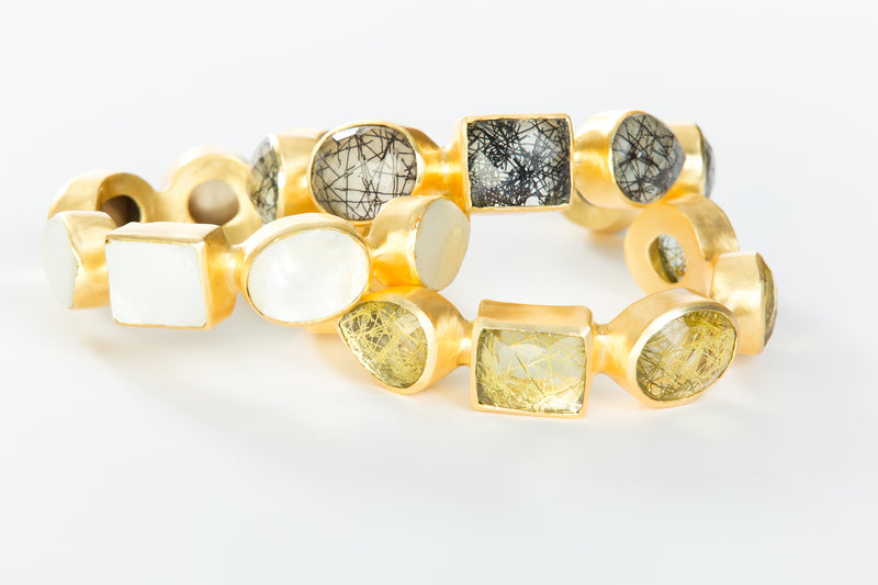Natural white mother-of-pearl stones set in brass and 18k electro-gold plated. Adjusts to fit most wrists.